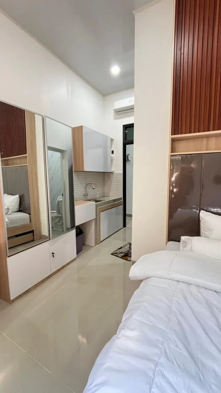 Interior kamar: tempat tidur, lemari tanam, dan meja rias dengan lantai keramik terang